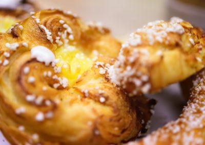 Close-up of Swedish wienerbröd with golden flaky layers, topped with pearl sugar and filled with rich vanilla custard.